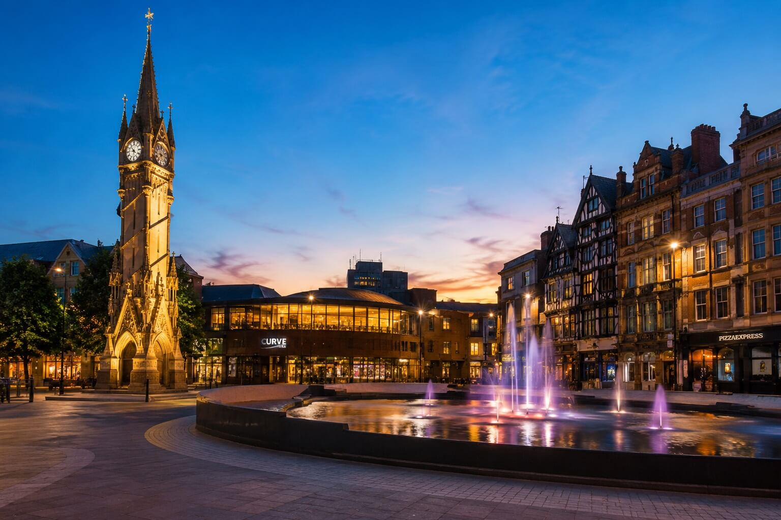 Leicester city centre at dusk showing the clock tower and fountains in an evening cityscape